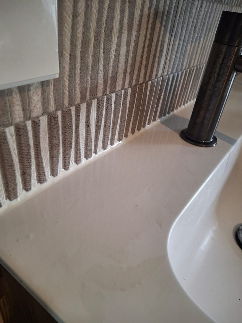 Close-up van een strak afgewerkte kitnaad langs een wastafel